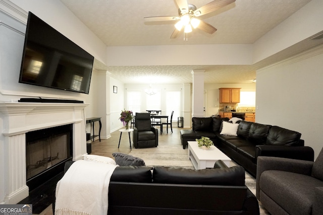 living area with wood finished floors, ceiling fan, a chandelier, a fireplace, and baseboards