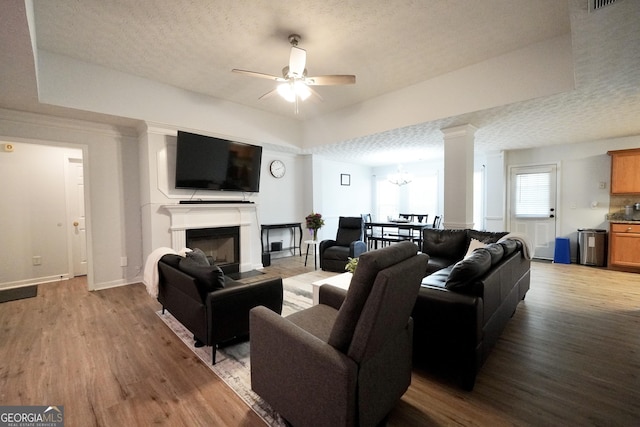 living room with a ceiling fan, wood finished floors, a textured ceiling, a fireplace, and baseboards