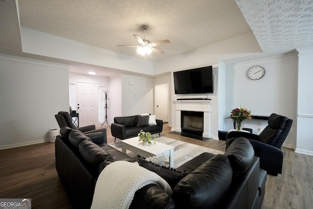 living room featuring baseboards, ceiling fan, wood finished floors, a textured ceiling, and a fireplace with flush hearth