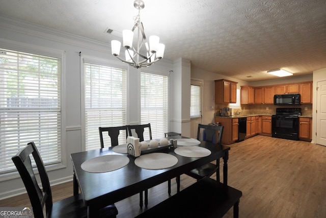 dining space featuring a chandelier, light wood-style flooring, a textured ceiling, crown molding, and baseboards