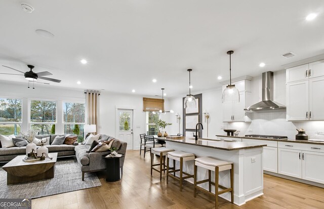 6402 Sycamore Dr, Hoschton, GA 30548 - kitchen with wall chimney exhaust hood, open floor plan, dark countertops, stainless steel gas cooktop, and recessed lighting