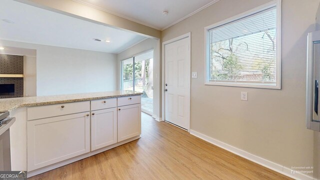 2280 Raleigh Dr, Augusta, GA 30904 - kitchen with light wood-style flooring, baseboards, ornamental molding, white cabinets, and light stone counters