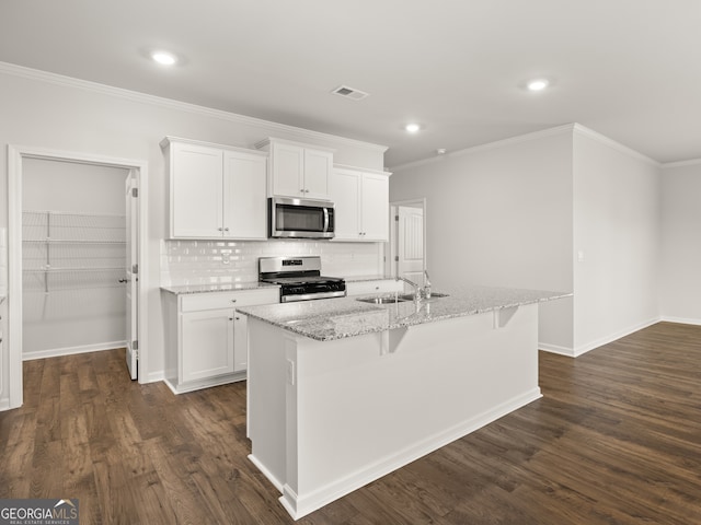 kitchen featuring appliances with stainless steel finishes, a sink, white cabinets, a center island with sink, and crown molding