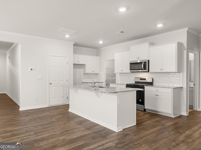 kitchen with appliances with stainless steel finishes, white cabinets, crown molding, tasteful backsplash, and an island with sink