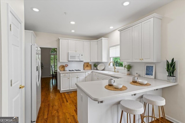 1444 Merrifield Ln, Marietta, GA 30062 - kitchen featuring white appliances, a sink, a peninsula, decorative backsplash, and white cabinets