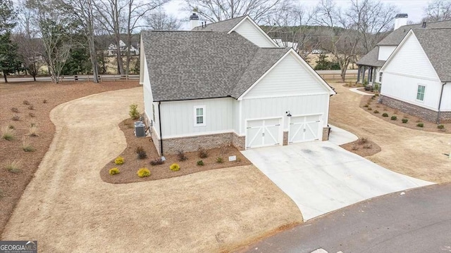 1325 Silo Bnd, Watkinsville, GA 30677 - view of side of home with roof with shingles, concrete driveway, a garage, central AC unit, and board and batten siding