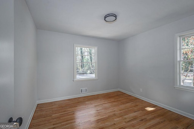 unfurnished room featuring healthy amount of natural light, wood finished floors, and baseboards
