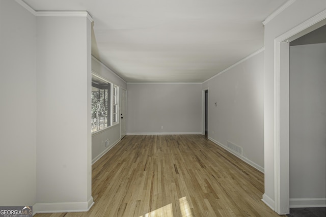 empty room with wood finished floors, baseboards, and ornamental molding