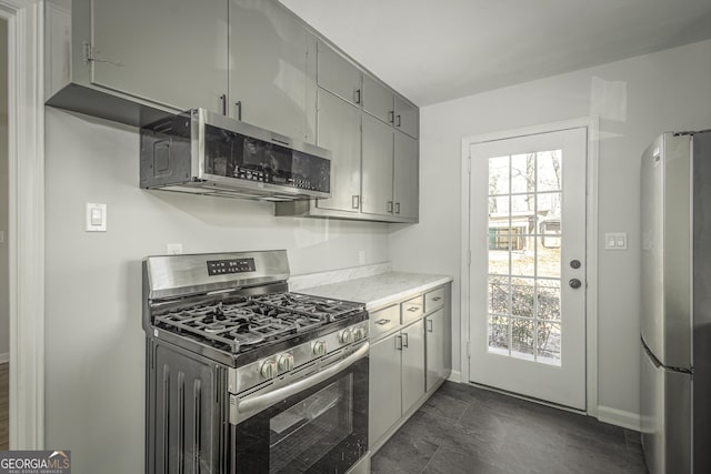 kitchen featuring appliances with stainless steel finishes, gray cabinetry, baseboards, and light stone countertops