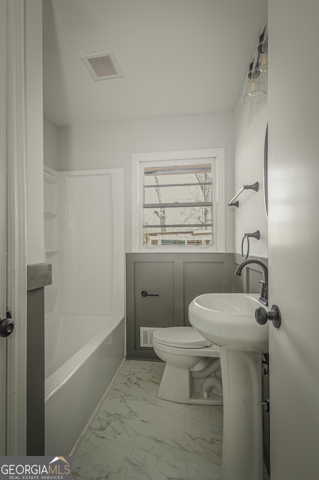 full bath with marble look tiles and toilet