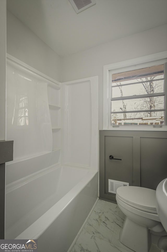 full bathroom with toilet and marble look tiles