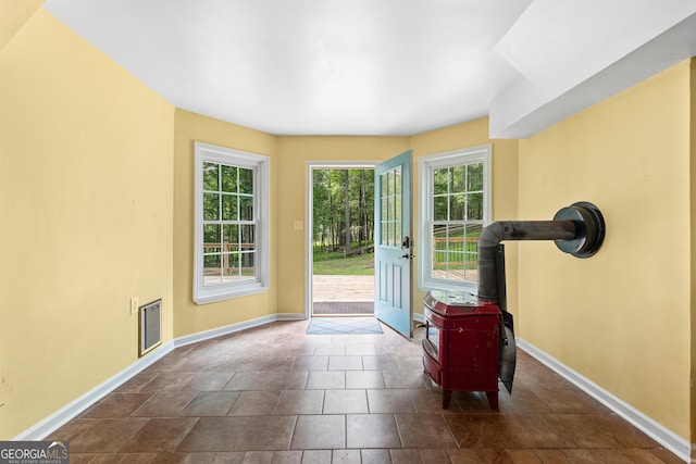 entryway featuring a wood stove, baseboards, and healthy amount of natural light