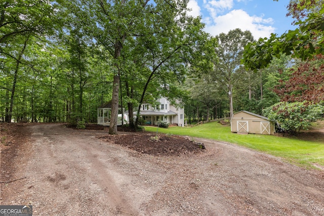 view of front of house featuring dirt driveway, a front yard, and an outbuilding
