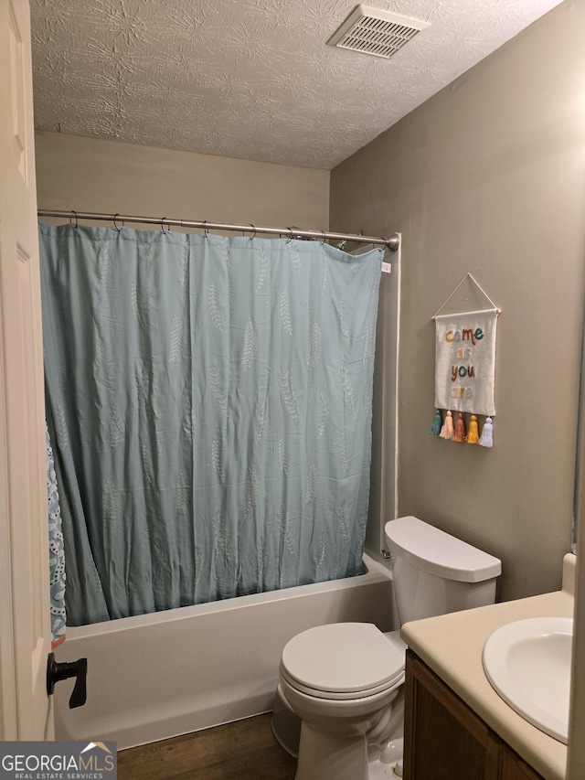 full bath featuring shower / bathtub combination with curtain, wood finished floors, a textured ceiling, toilet, and vanity