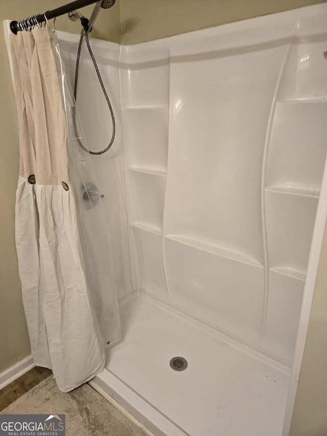 full bath with a stall shower and wood finished floors