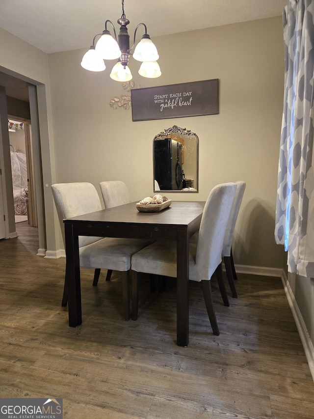 dining space featuring a chandelier, baseboards, and wood finished floors