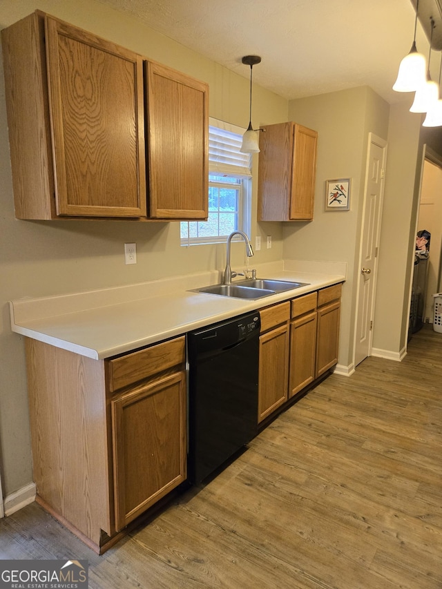 kitchen featuring dishwasher, a sink, light wood-style flooring, and baseboards