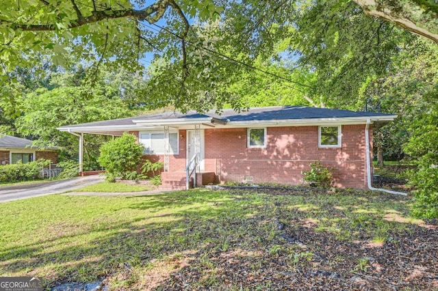 single story home with asphalt driveway, a front yard, brick siding, entry steps, and a carport
