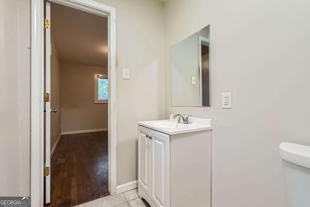 bathroom with vanity, toilet, baseboards, and wood finished floors