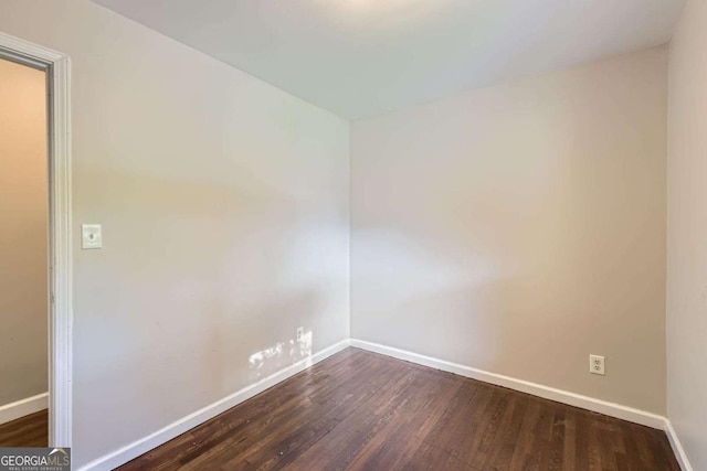 unfurnished room with baseboards and dark wood finished floors