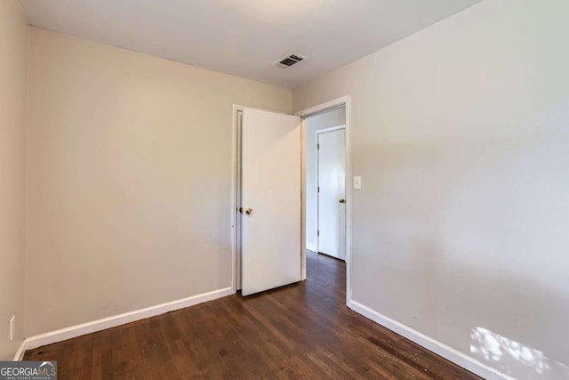 empty room with baseboards and dark wood-type flooring