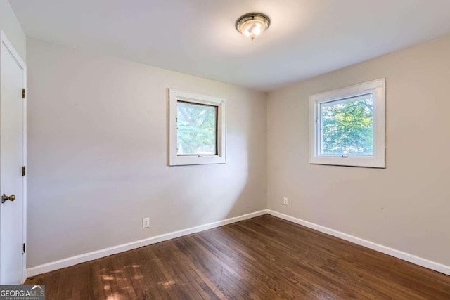 unfurnished room featuring plenty of natural light, baseboards, and wood finished floors
