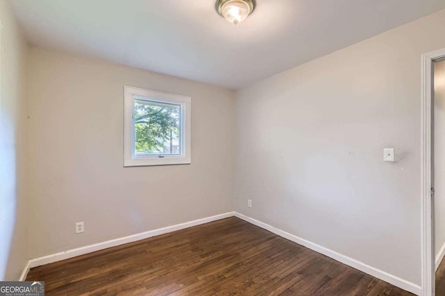 empty room featuring baseboards and dark wood-type flooring