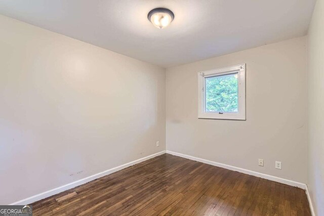 unfurnished room with baseboards and dark wood finished floors