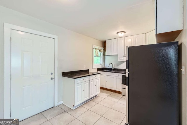 kitchen with freestanding refrigerator, a sink, white cabinets, and dark countertops