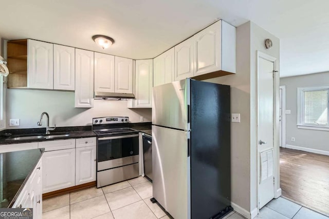 kitchen featuring stainless steel appliances, a sink, under cabinet range hood, light tile patterned floors, and white cabinetry