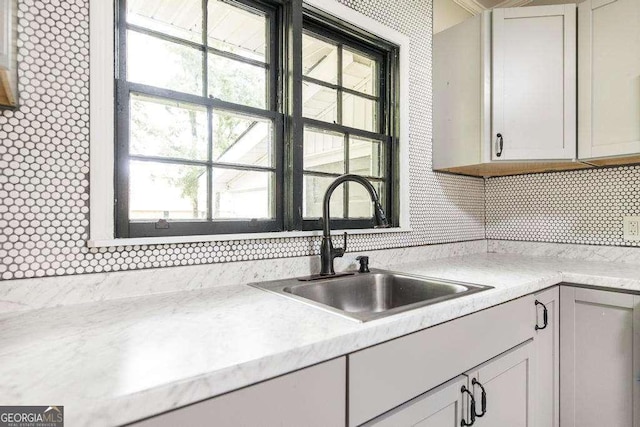 kitchen with a sink, light countertops, and tasteful backsplash