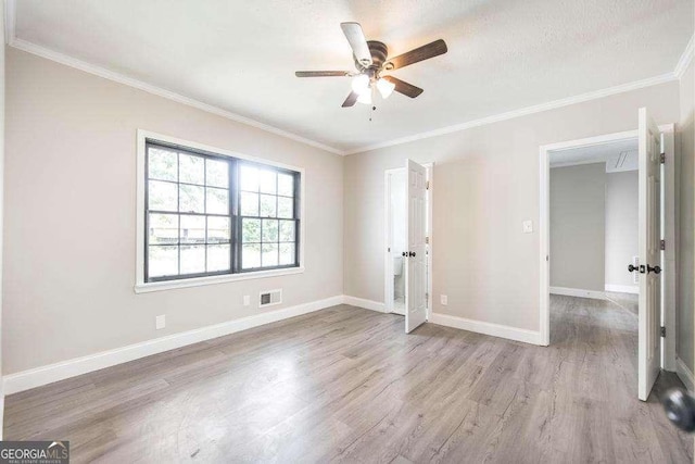 empty room with wood finished floors, a ceiling fan, crown molding, and baseboards