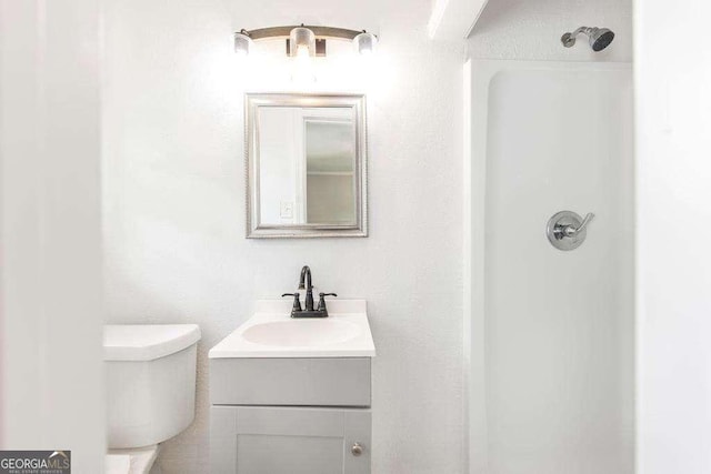 bathroom featuring vanity, toilet, and a shower
