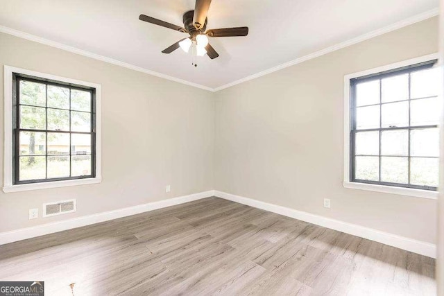 unfurnished room featuring wood finished floors, healthy amount of natural light, baseboards, and crown molding