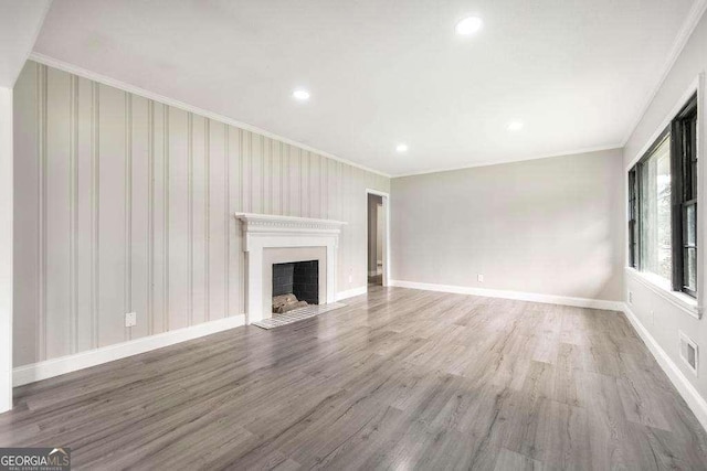 unfurnished living room featuring crown molding, a fireplace, wood finished floors, recessed lighting, and baseboards