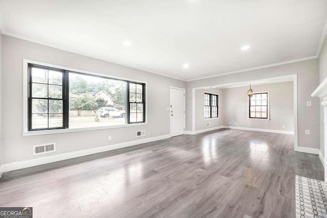 unfurnished living room featuring plenty of natural light, crown molding, wood finished floors, baseboards, and recessed lighting