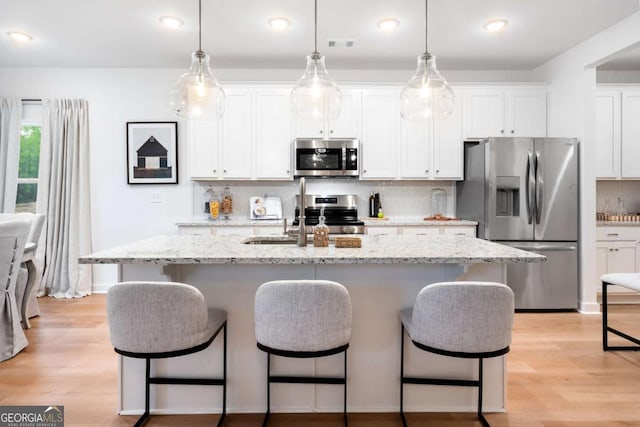 3354 Traditions Way, Jefferson, GA 30549 - kitchen with stainless steel appliances, a breakfast bar, a center island with sink, backsplash, and white cabinetry