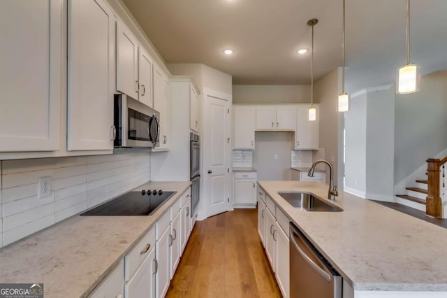 3354 Traditions Way, Jefferson, GA 30549 - kitchen with stainless steel appliances, a sink, white cabinets, light wood-style flooring, and an island with sink