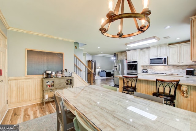5220 Wild Cedar Dr, Buford, GA 30518 - dining area featuring a chandelier, light wood-style flooring, stairs, crown molding, and a wainscoted wall