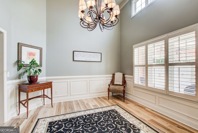 5220 Wild Cedar Dr, Buford, GA 30518 - sitting room featuring wood finished floors, a chandelier, a towering ceiling, a decorative wall, and wainscoting