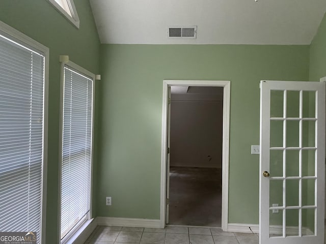 unfurnished bedroom with vaulted ceiling, light tile patterned floors, baseboards, and a walk in closet