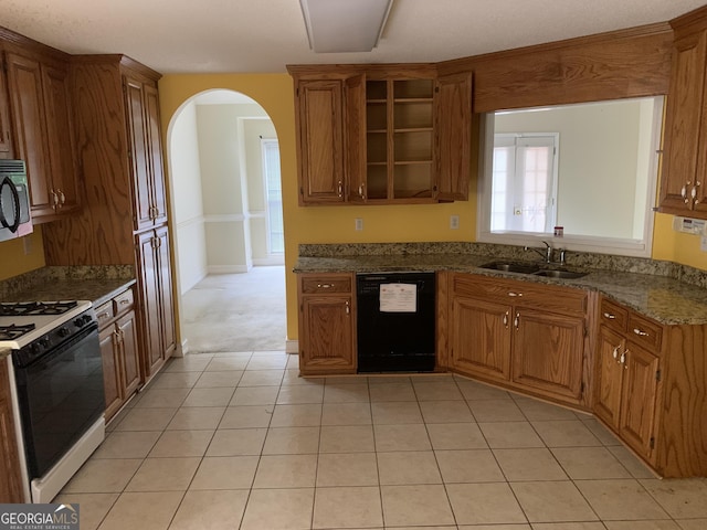kitchen featuring black appliances, a sink, arched walkways, and brown cabinetry