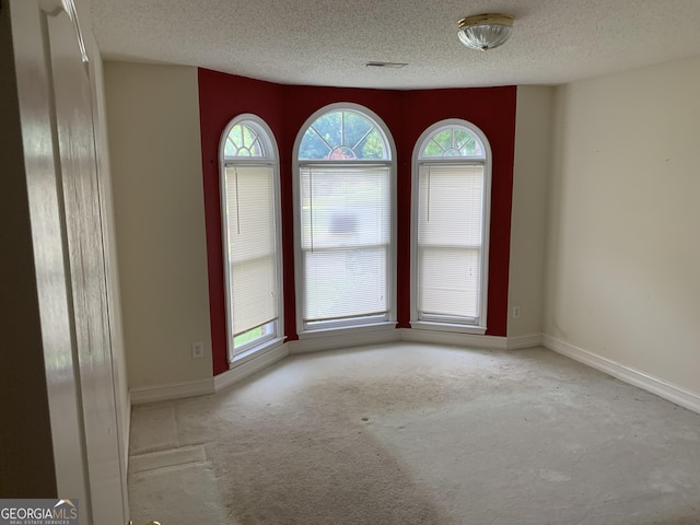 carpeted empty room with a textured ceiling and baseboards