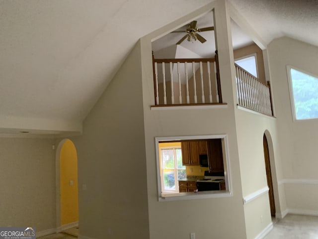 unfurnished living room with arched walkways, ceiling fan, plenty of natural light, and high vaulted ceiling