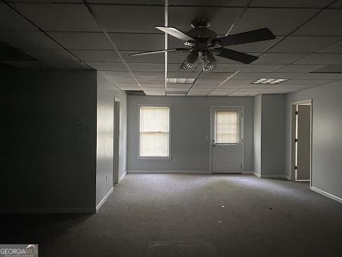 empty room with a drop ceiling, baseboards, ceiling fan, and carpet floors