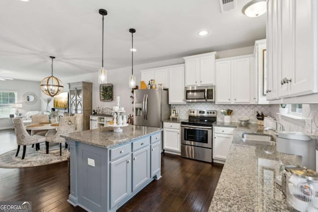 kitchen featuring stainless steel appliances, white cabinetry, backsplash, light stone counters, and dark wood-type flooring