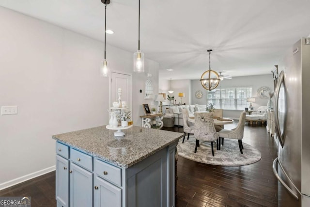 kitchen with freestanding refrigerator, a center island, a chandelier, dark wood finished floors, and decorative light fixtures