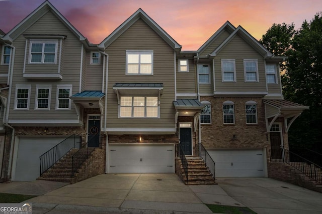 view of property featuring a garage, brick siding, stairway, and concrete driveway