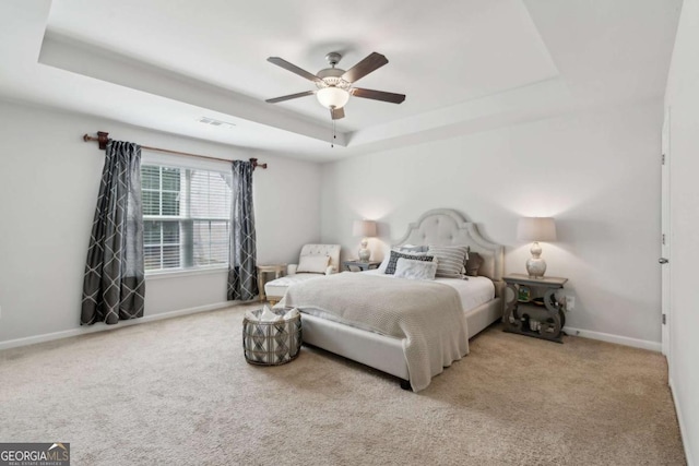 carpeted bedroom with a tray ceiling, baseboards, and ceiling fan
