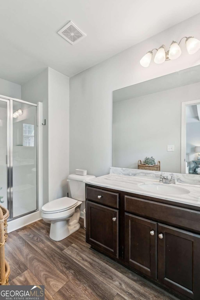 bathroom featuring wood finished floors, vanity, a stall shower, and toilet